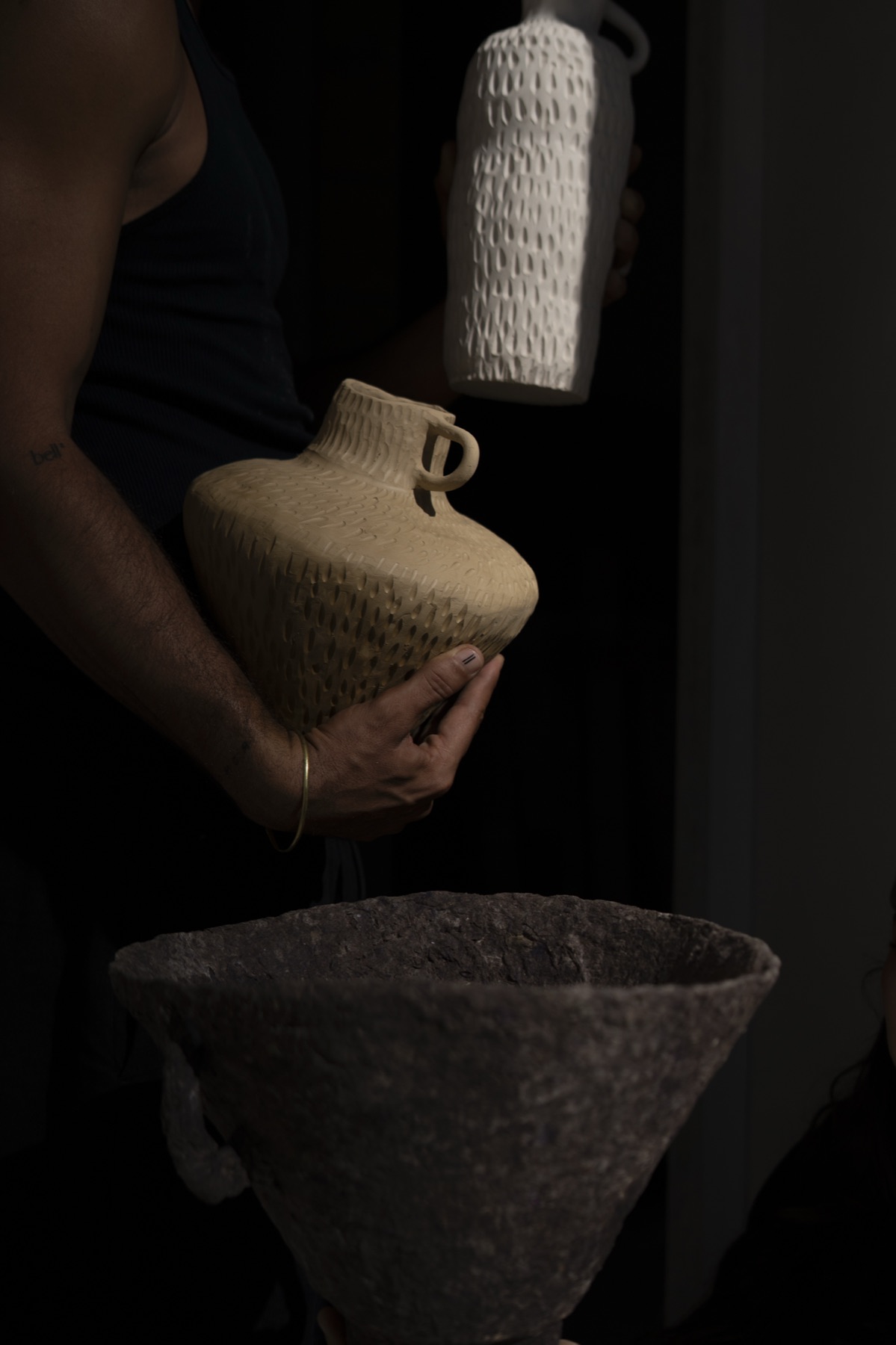 A ribbed vessel lifted in darkness above a wide conical bowl.