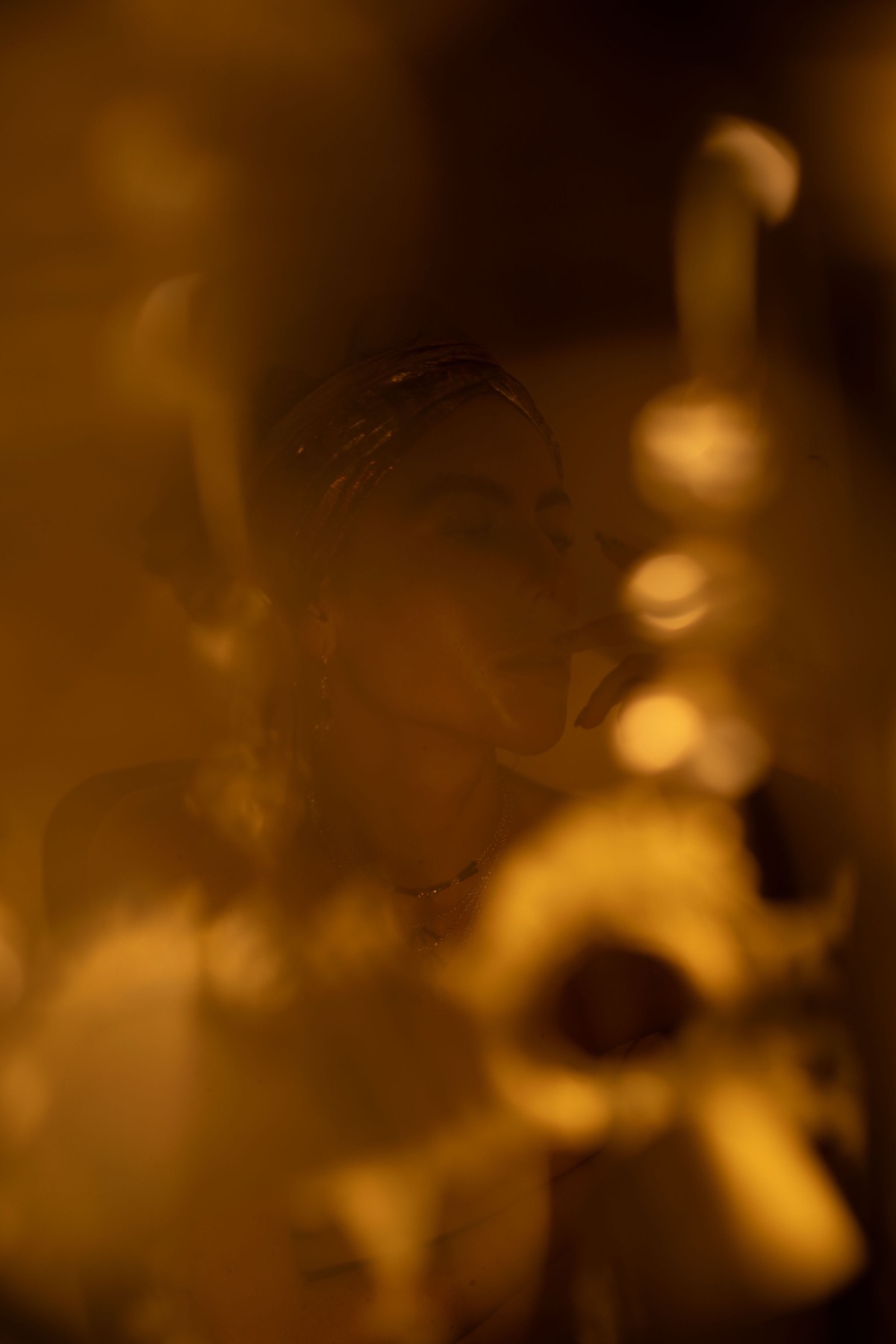 A woman's face seen through candlelight and out-of-focus gold ornaments.